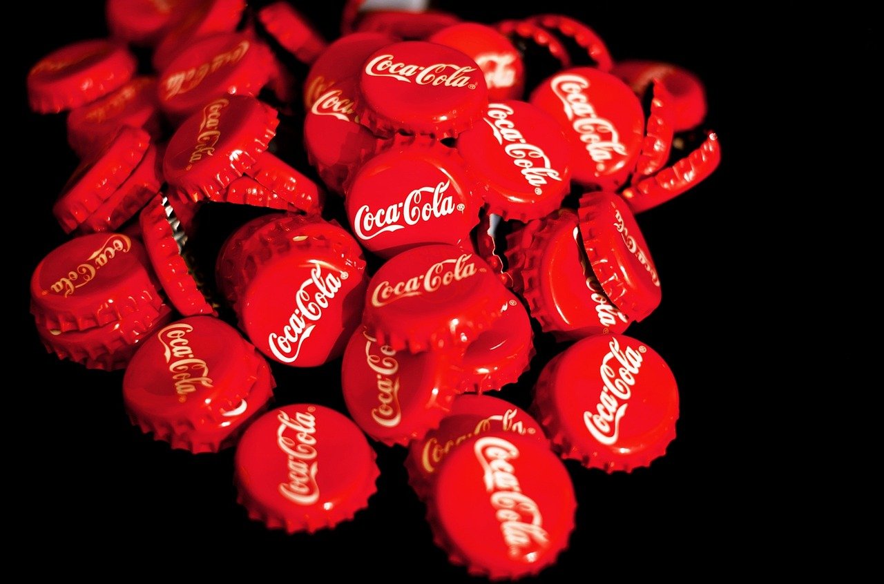 Exemplos de proposta única de valor de marcas famosas - Tampas de garrafas de Coca-Cola sobre um fundo reto.