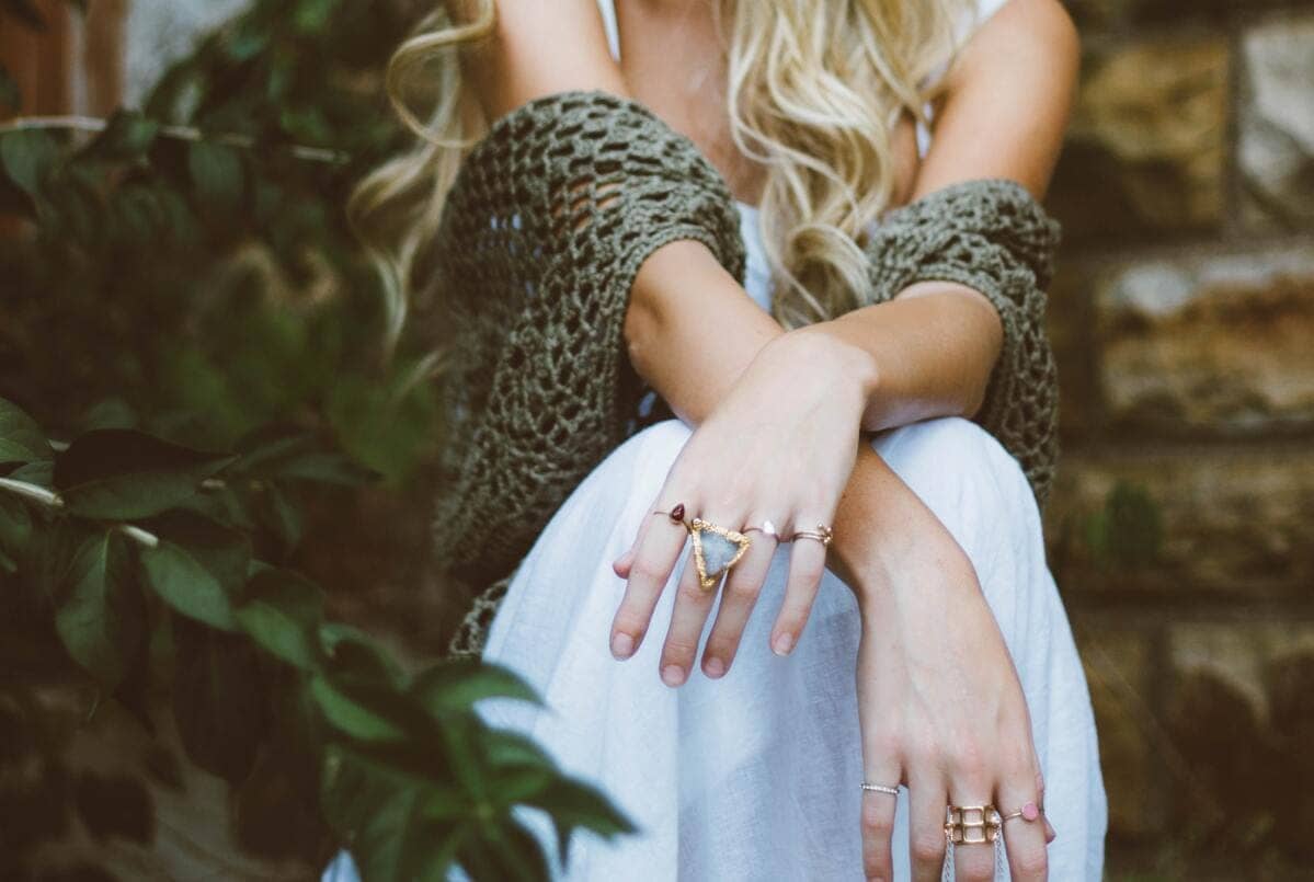 Una ragazza seduta che indossa diversi anelli alle dita