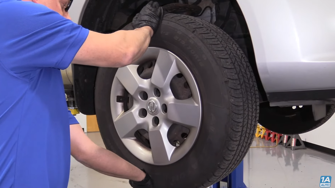 Mechanic grabbing the tire at the 12 and 6 o'clock positions to test for ball joints