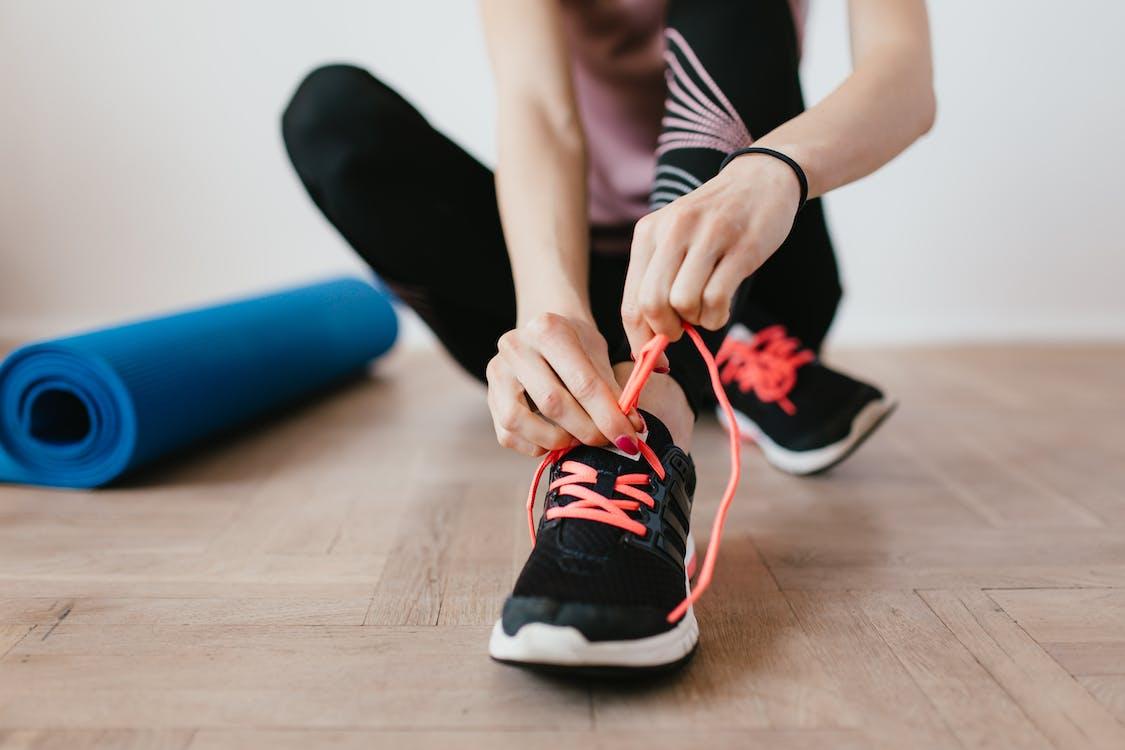 Free Crop young sportswoman tying shoelaces on sneakers Stock Photo