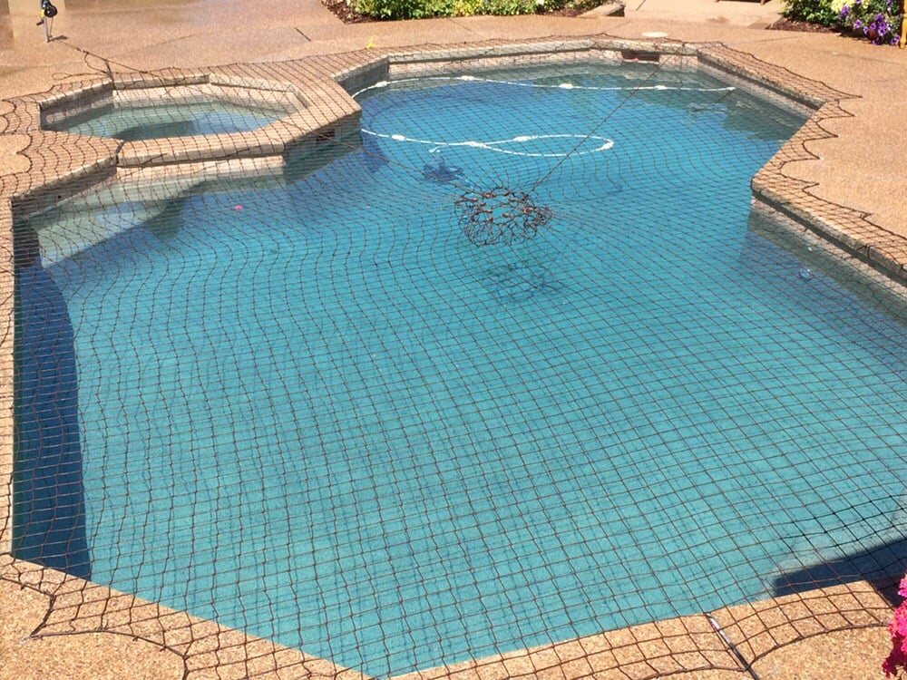 Brown swimming pool safety net installed on a backyard pool and hot tub