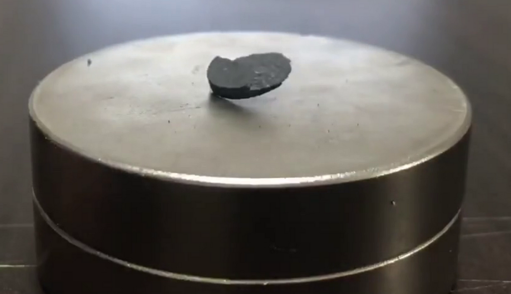 A black piece of coal on a round metal container

Description automatically generated