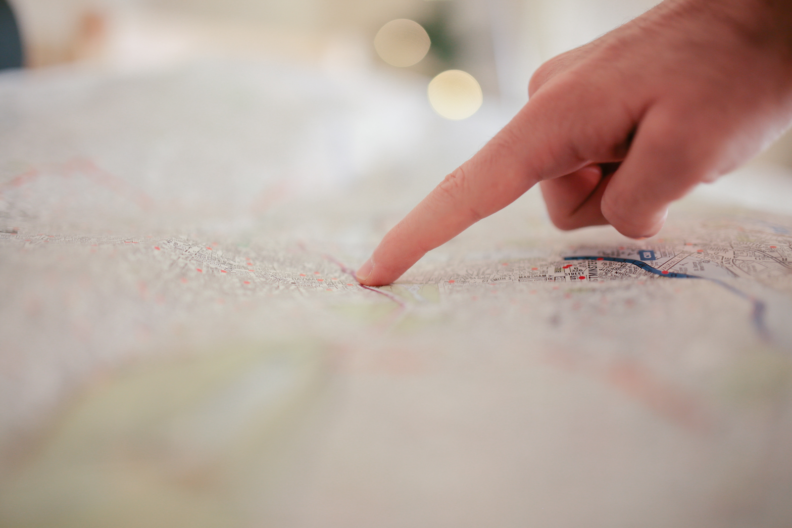 Finger touching a point on a map with a blurry background and foreground.