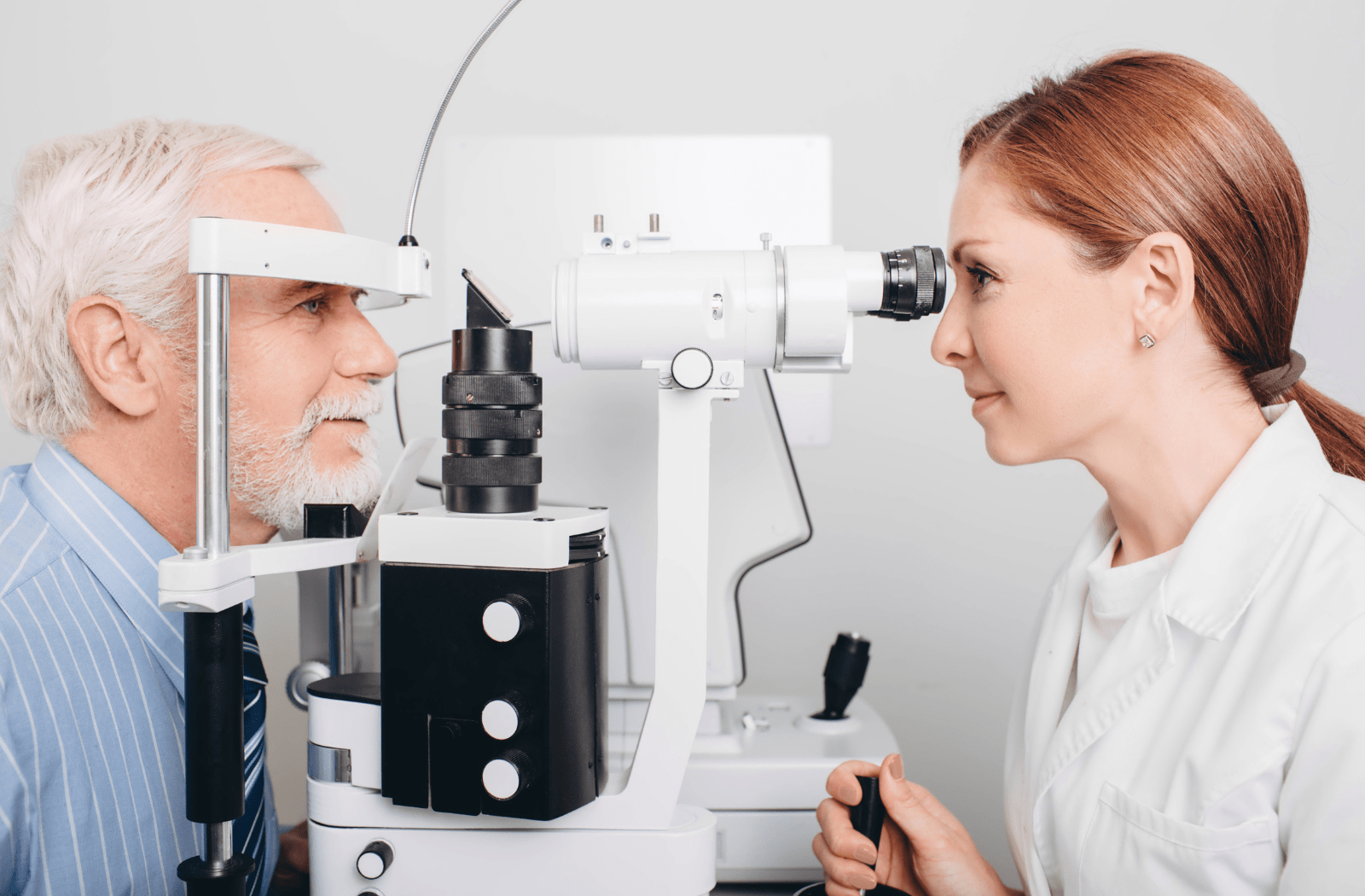 A female optometrist examines a male senior citizen patients eyes