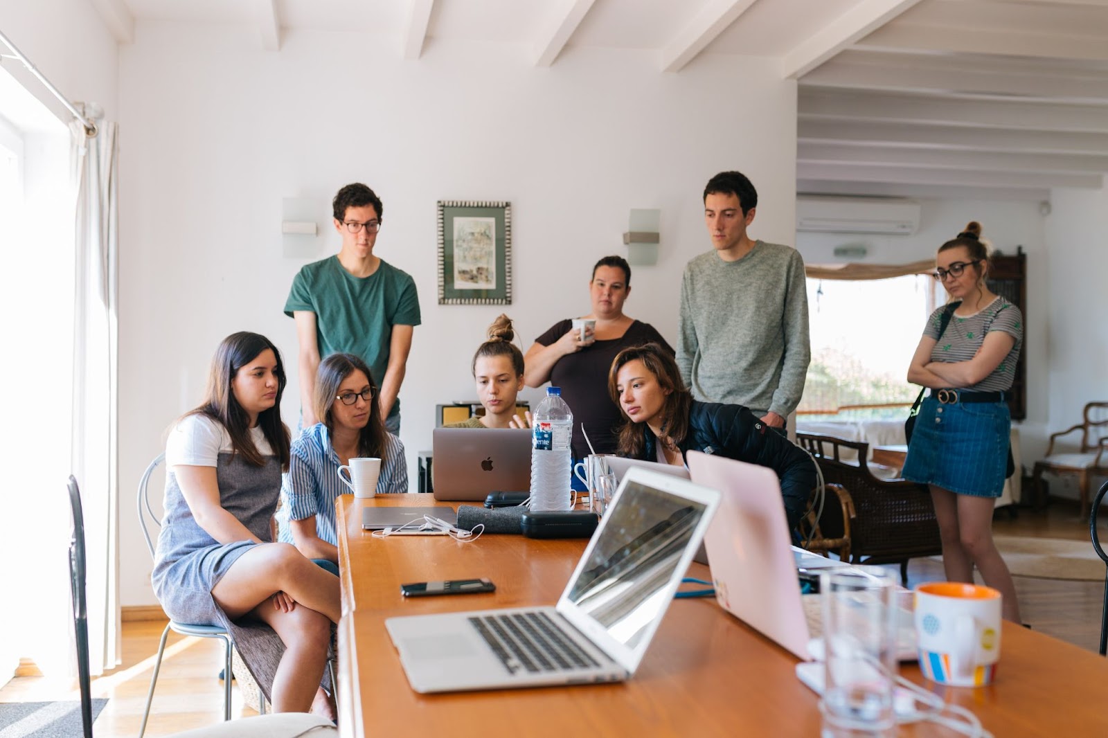 Image of a group of colleagues crowded round a laptop looking at it.