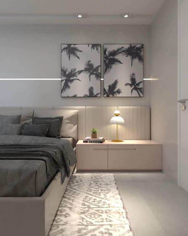 Quarto com decoração em cor neutra, cabeceira da cama  branca estofada na largura da parede, criado mudo branco, piso porcelanato branco e quadro preto e branco na parede de fundo