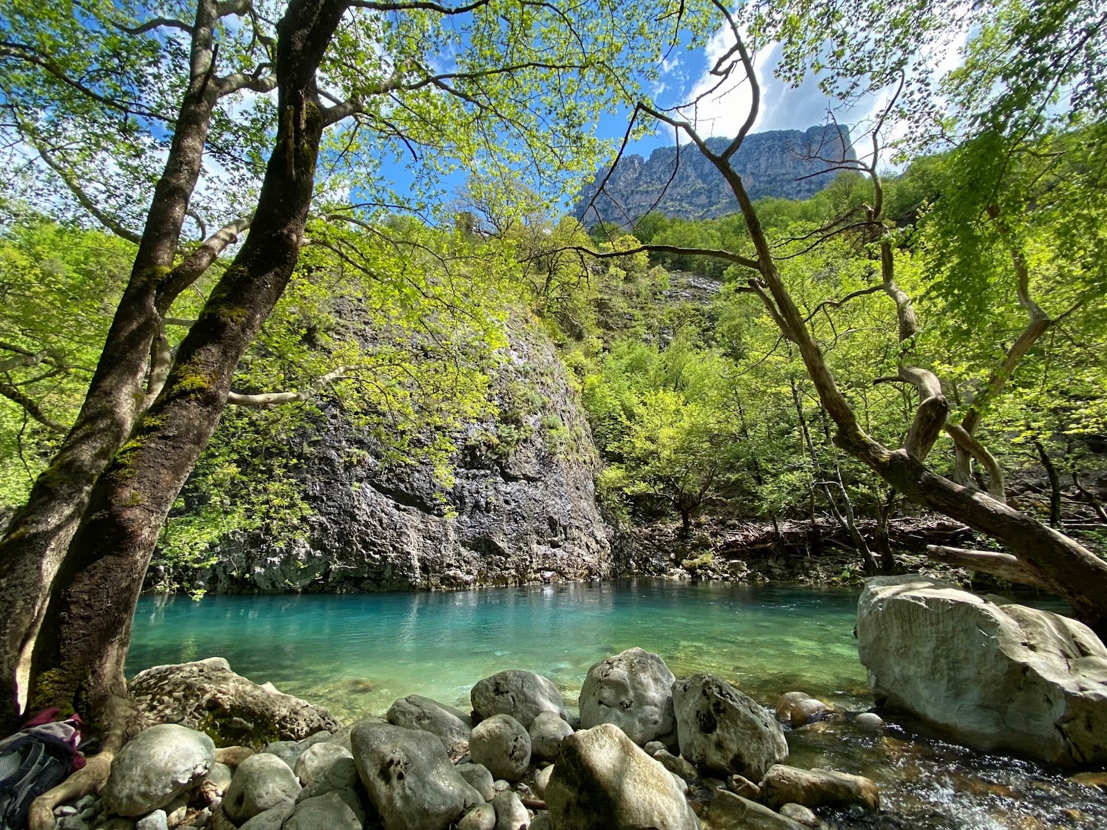 Turquoise river water lined by green trees and rocky banks