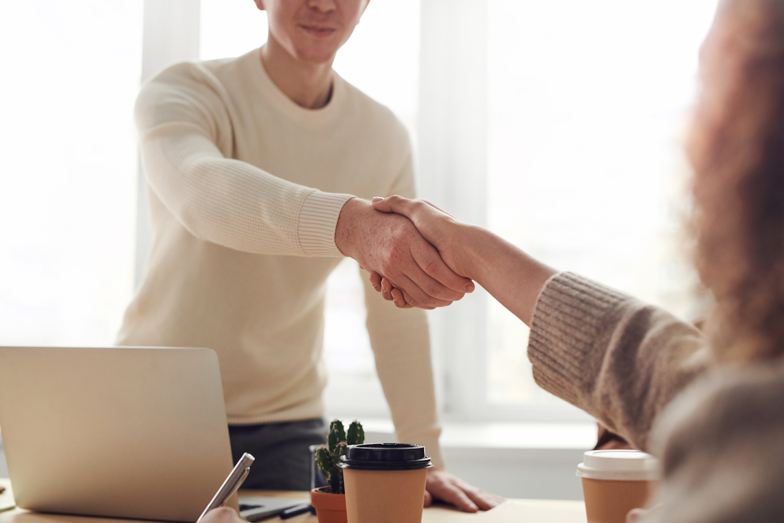 Two people shaking hands in a business setting.