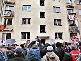 Protestierende vor Wohnhaus mit Transparenten: »Miethaie zu Fischstäbchen«, »Die Stadt gehört uns«, »Finger weg!«, »Alle für Kalle«, »Stop Zwansräumungen«.