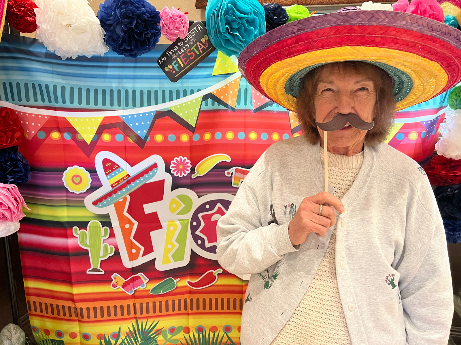 a senior woman in sombrero and mustache prop for cinco de mayo
