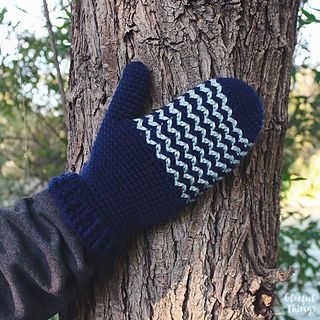 a hand touching a trunk of tree while wearing little peaks mittens
