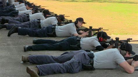 A group of people lying on the ground with guns

Description automatically generated with medium confidence