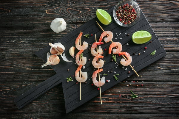 Fresh shrimp on skewers with garlic, lime, and herbs surrounding it