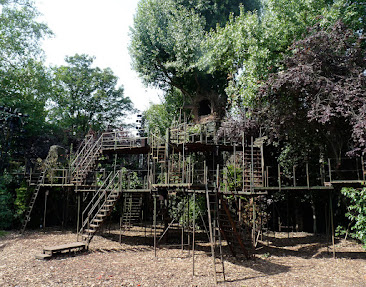 A wooden structure on what appears to be a bed of woodchips. There are many levels, and staircases connecting them