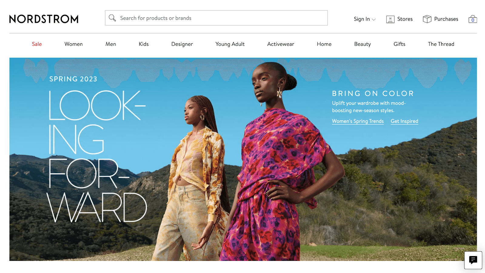 Fashion Industry Loyalty Program Examples–A screenshot from Nordstrom’s homepage. There is an image of two Black women standing outside in front of a green landscape, wearing brightly-colored clothing. The text reads, “Spring 2023 Looking Forward.”