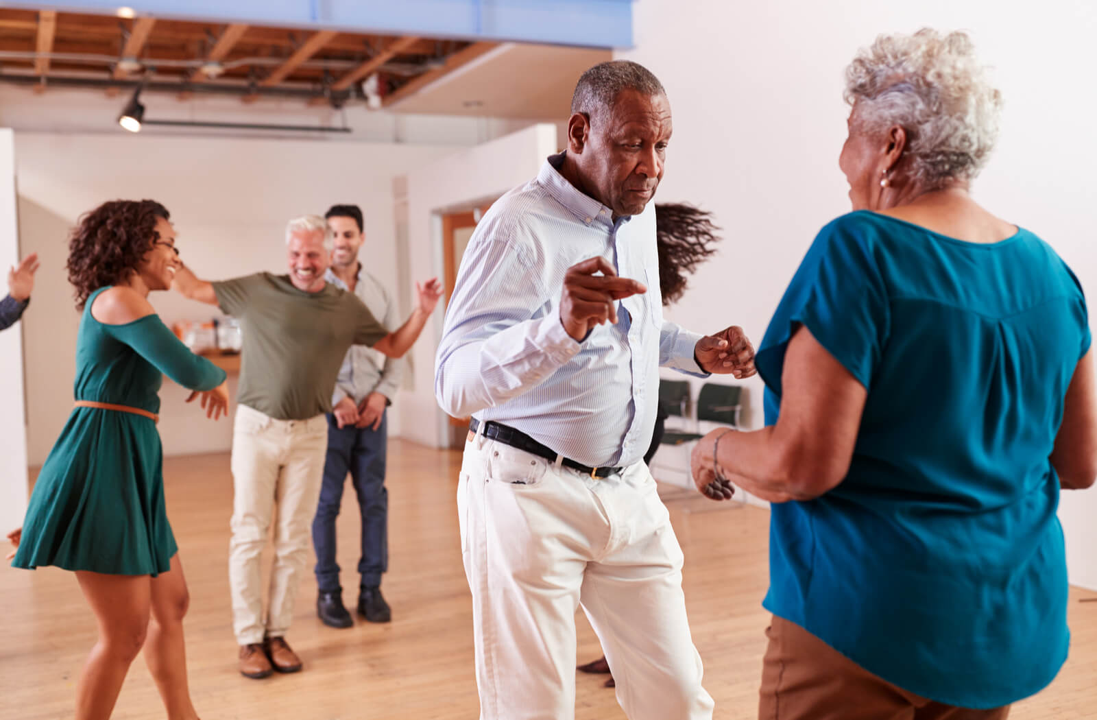 Two seniors dance in the foreground together, while three more people dance in the background behind them.