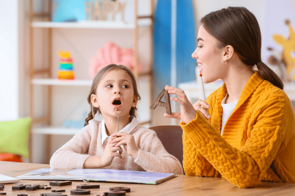 Speech therapist working with young girl in clinic.