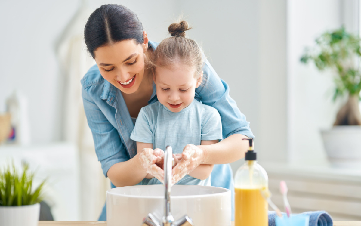 A mom and daughter using a bathroom sink to wash their hands.