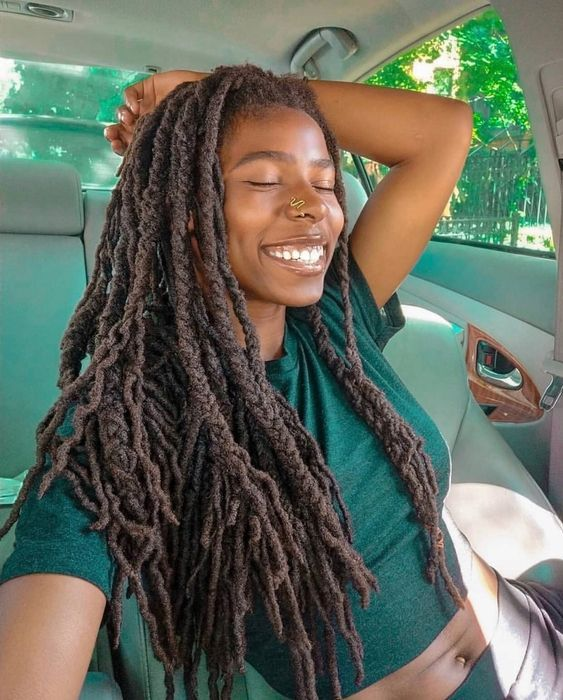 smiling lady wearing dreadlocks with extensions in a car