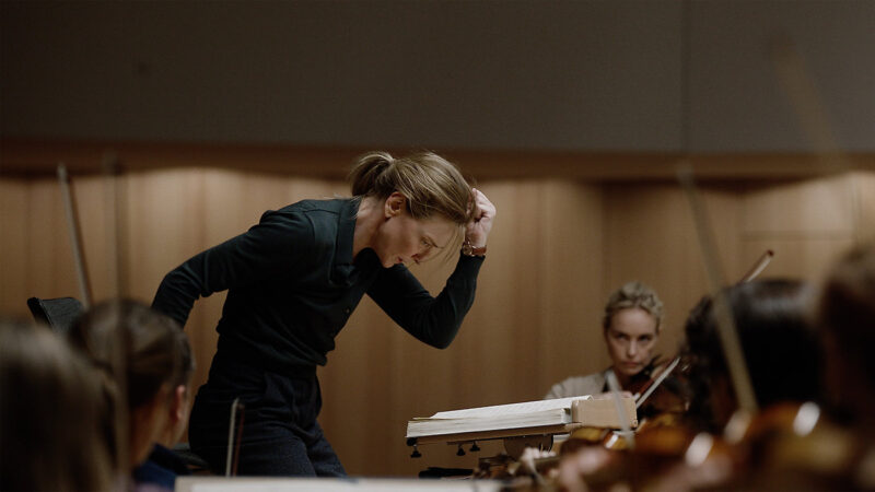 A woman leans over as she leads an orchestra