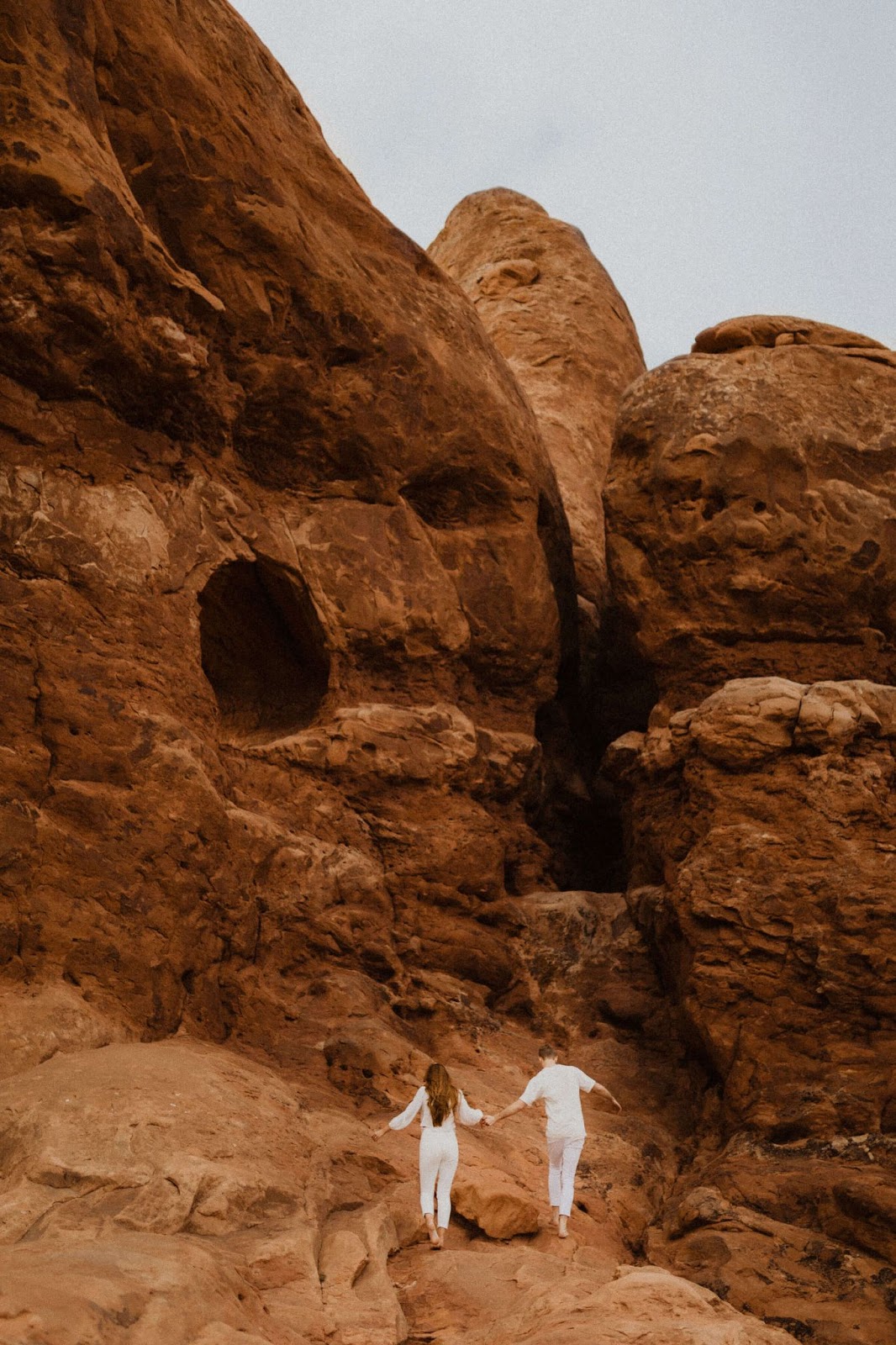 couple holding hands on rock formation in Moab