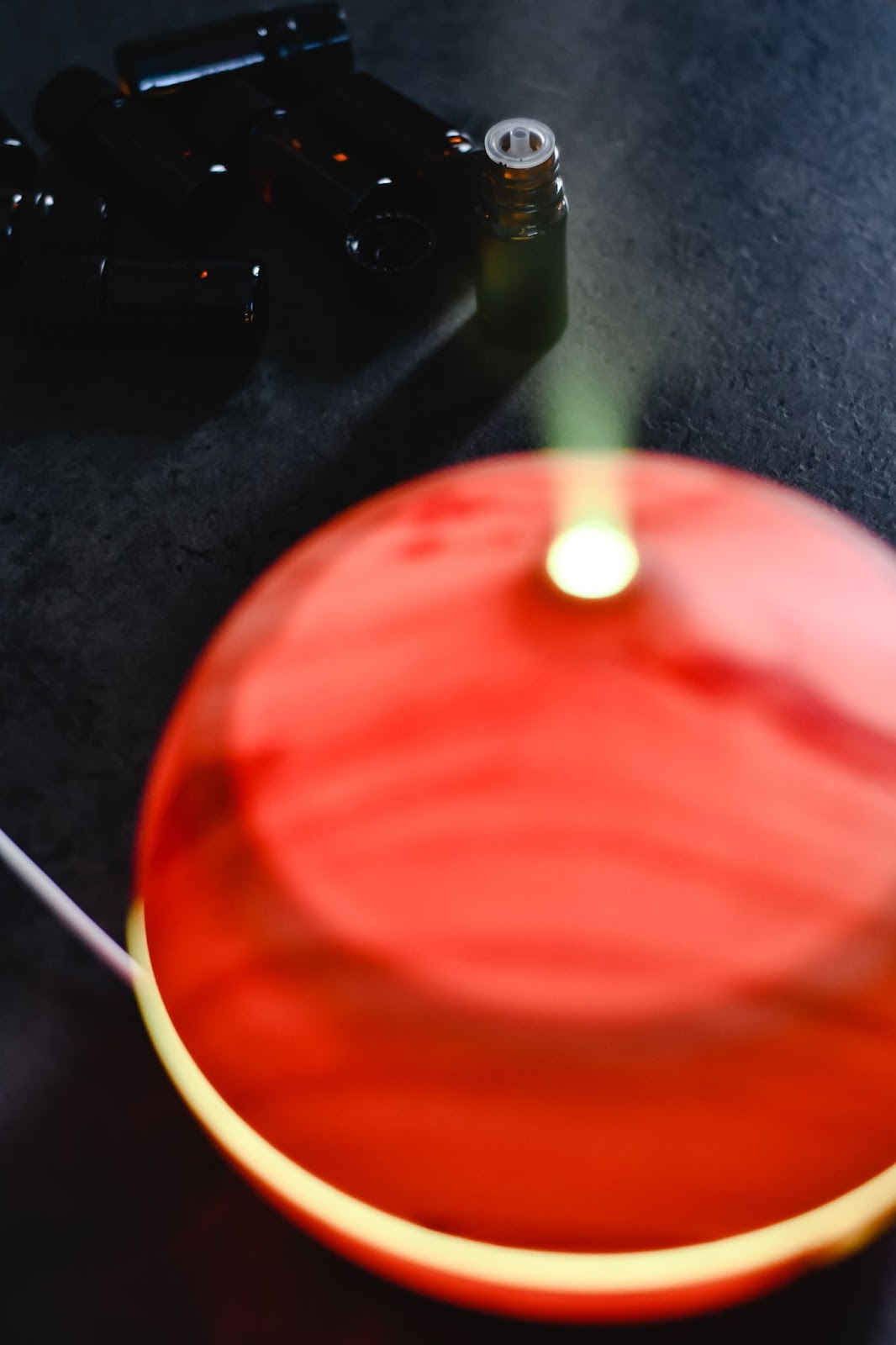 Close up shot of a red essential oil diffuser on black surface.