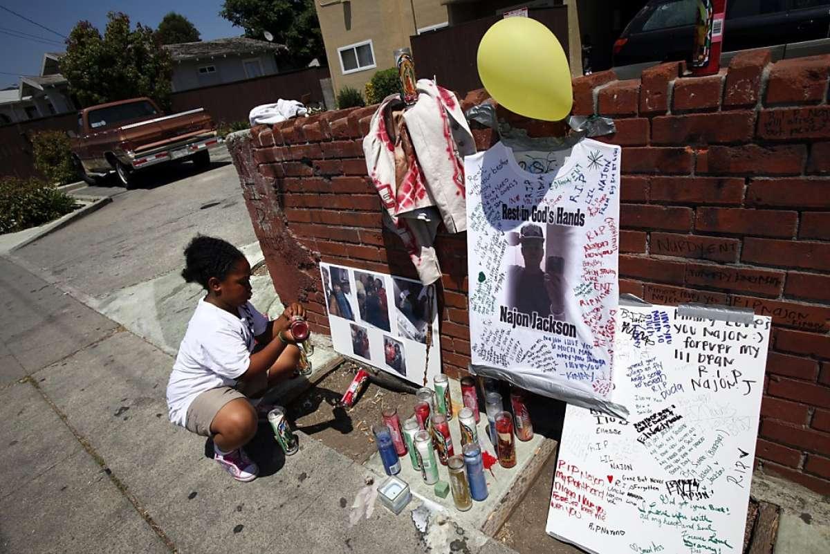 Sah-de Jackson, 10, straightens the memorial to her brother, Najon Jackson, 16, outside her grandmother's apartment in Oakland, Calif., Monday, August 1, 2011. Najon Jackson was shot and killed outside the apartment Saturday night.