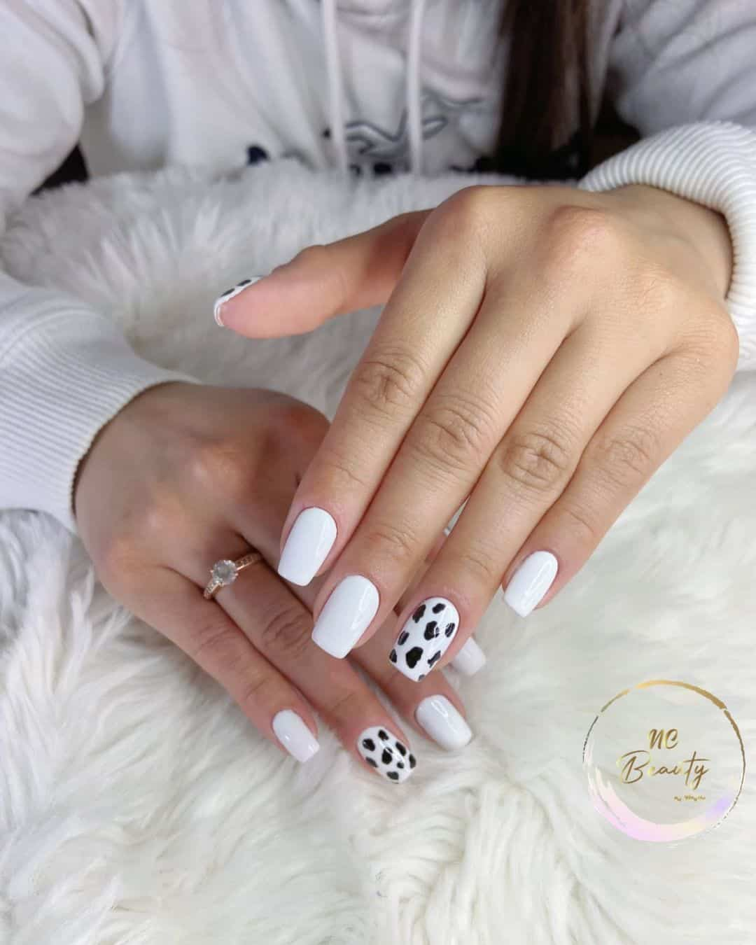 Full picture of a lady rocking white nails with some cow prints vibe 