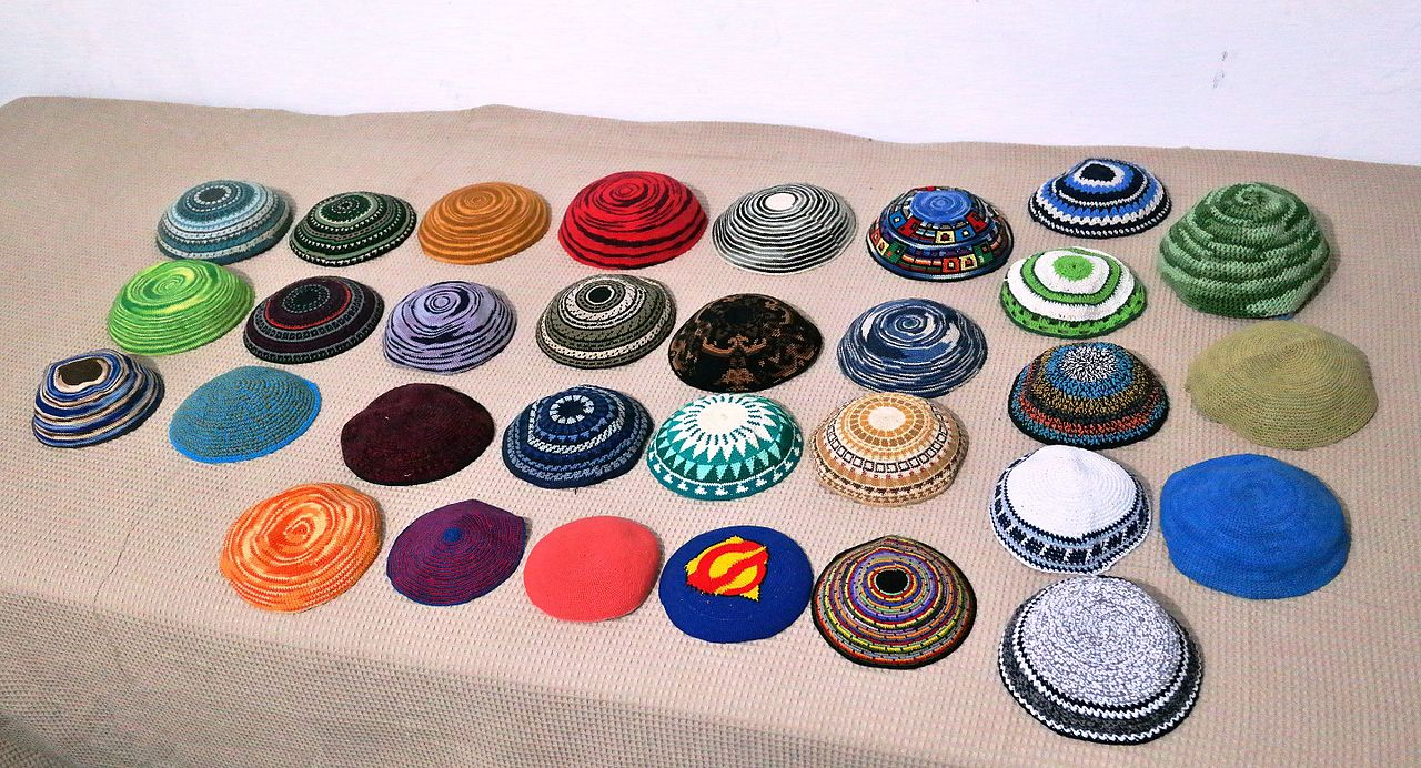 Lots of kippahs arranged neatly on a table.