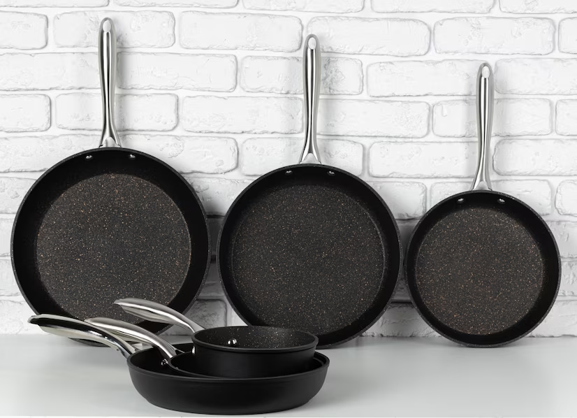 Various pans arranged on a table against a white brick wall