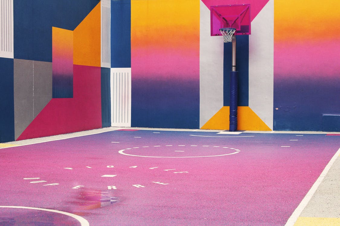 Image of a basketball court with geometric shapes and color gradients on the walls and floor.