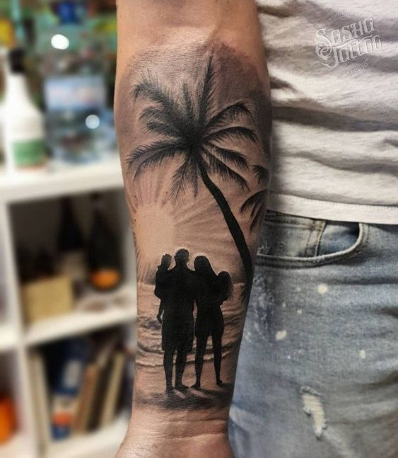 Guy shows off a family and palm tree tattoo design on his hand