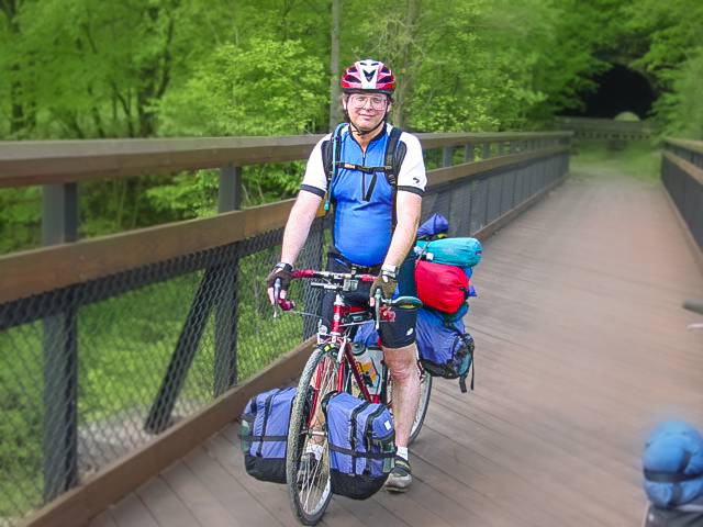 Man on a bicycle loaded with camping equipment. 