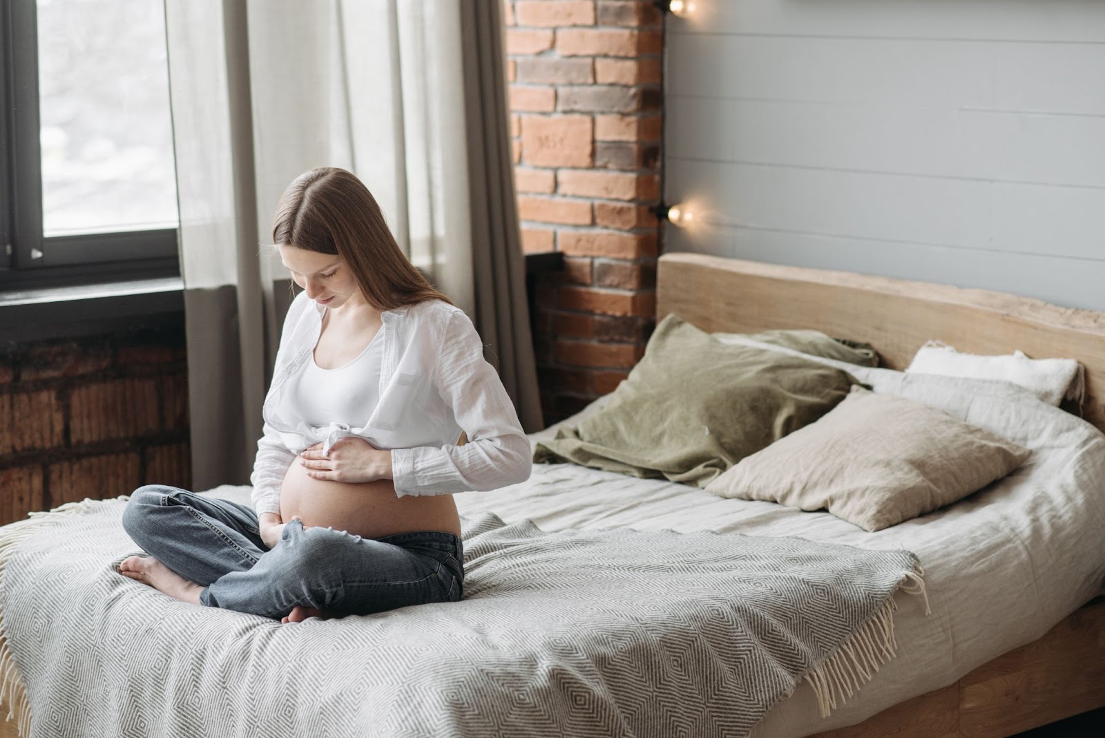 pregnant woman sitting in bed with her hand on belly