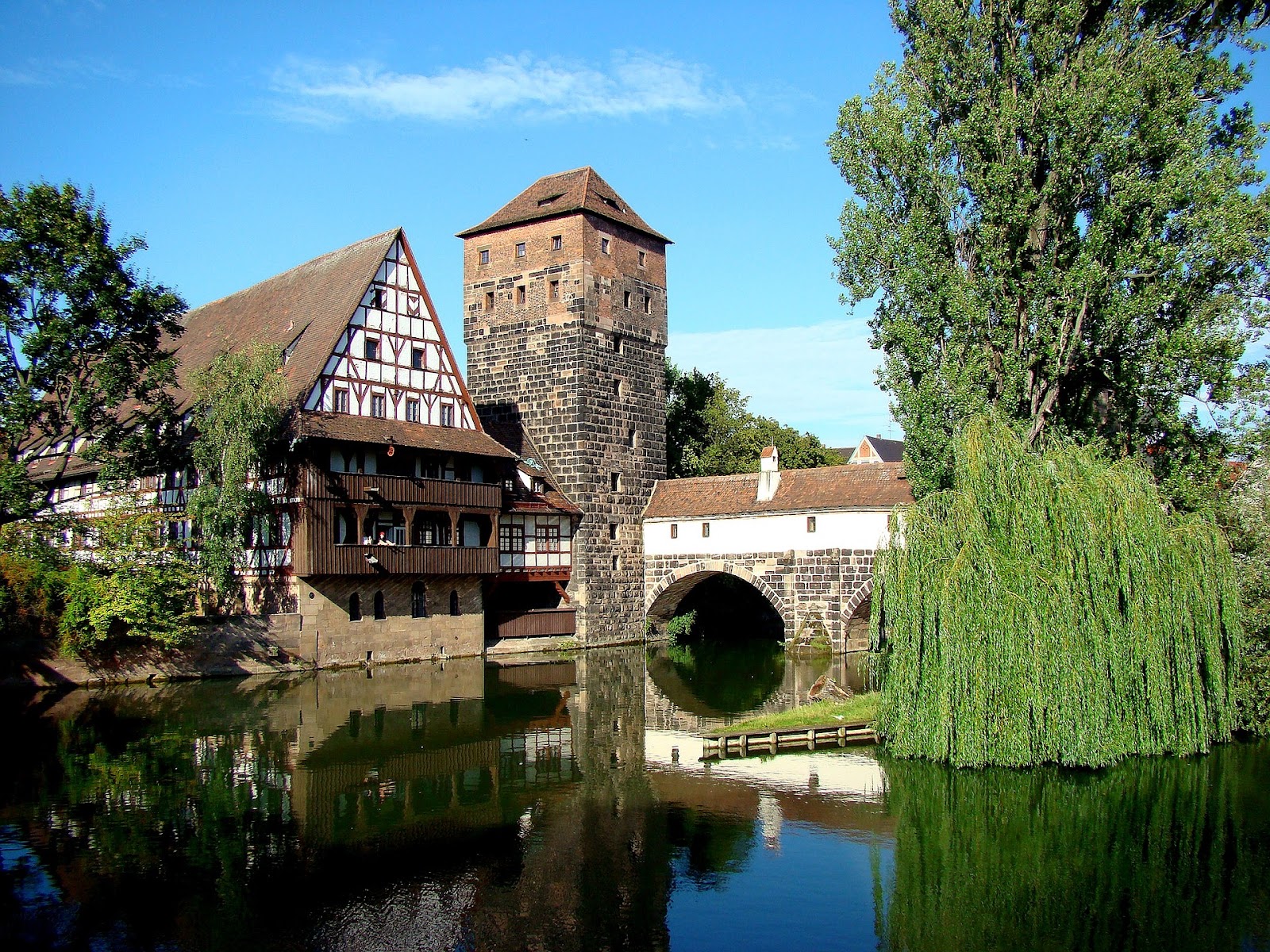 nuremberg medieval weinstadel structure next to river and green trees on a hot sunny day in germany