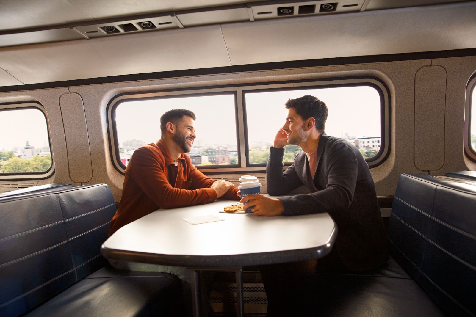 Two travelers share coffee at a table in the train's dining car.