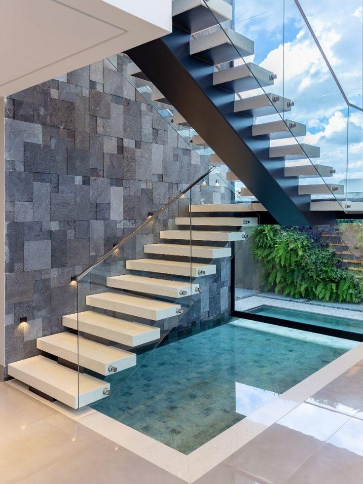 Escada moderna com degraus brancos vazado pendente na parede e corrimão com proteção de vidro