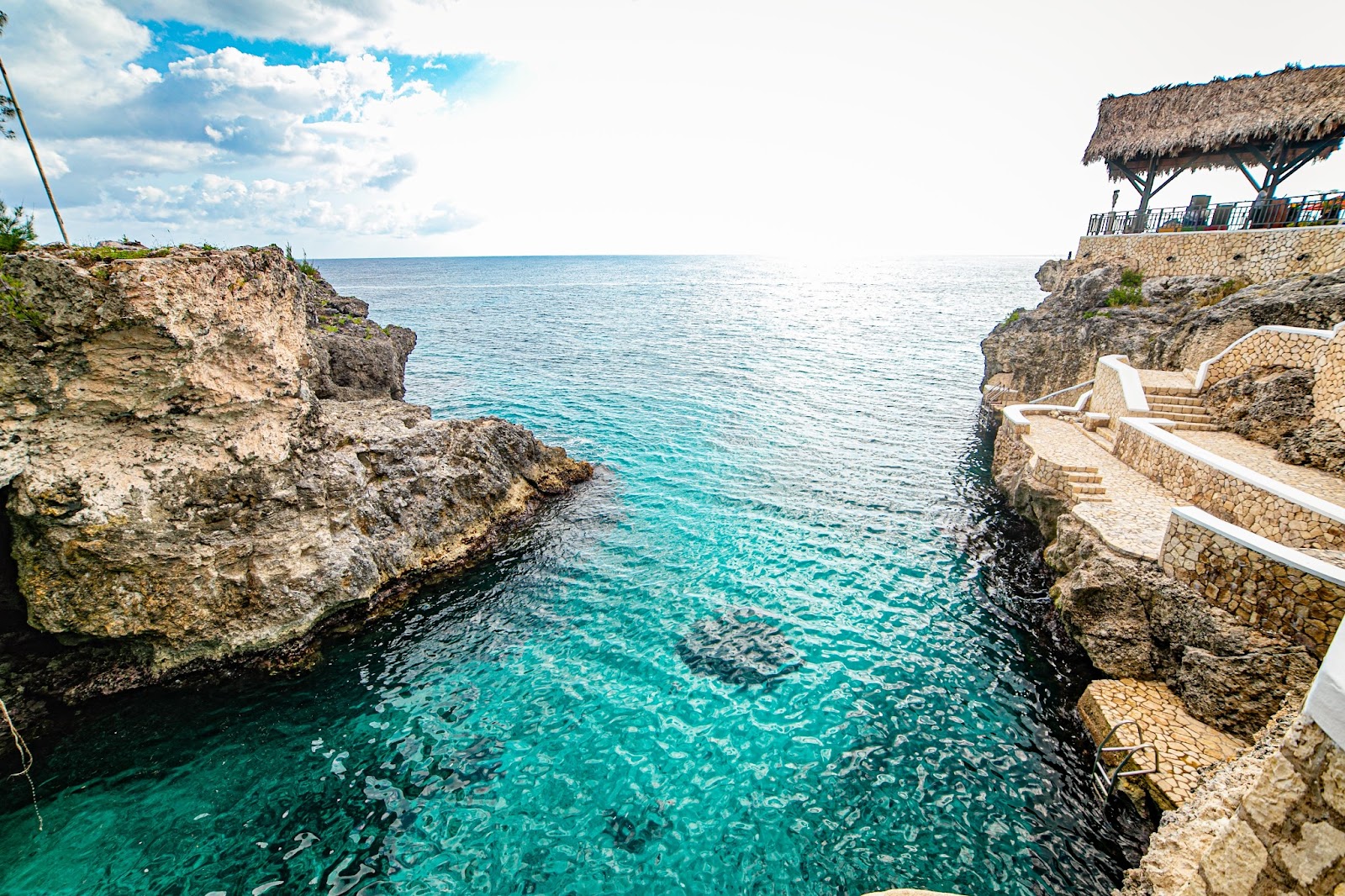 A captivating image from the top of 35-foot cliffs at Rick's Café in Negril, Jamaica. Experience delicious food and cliff jumping with a stunning view.