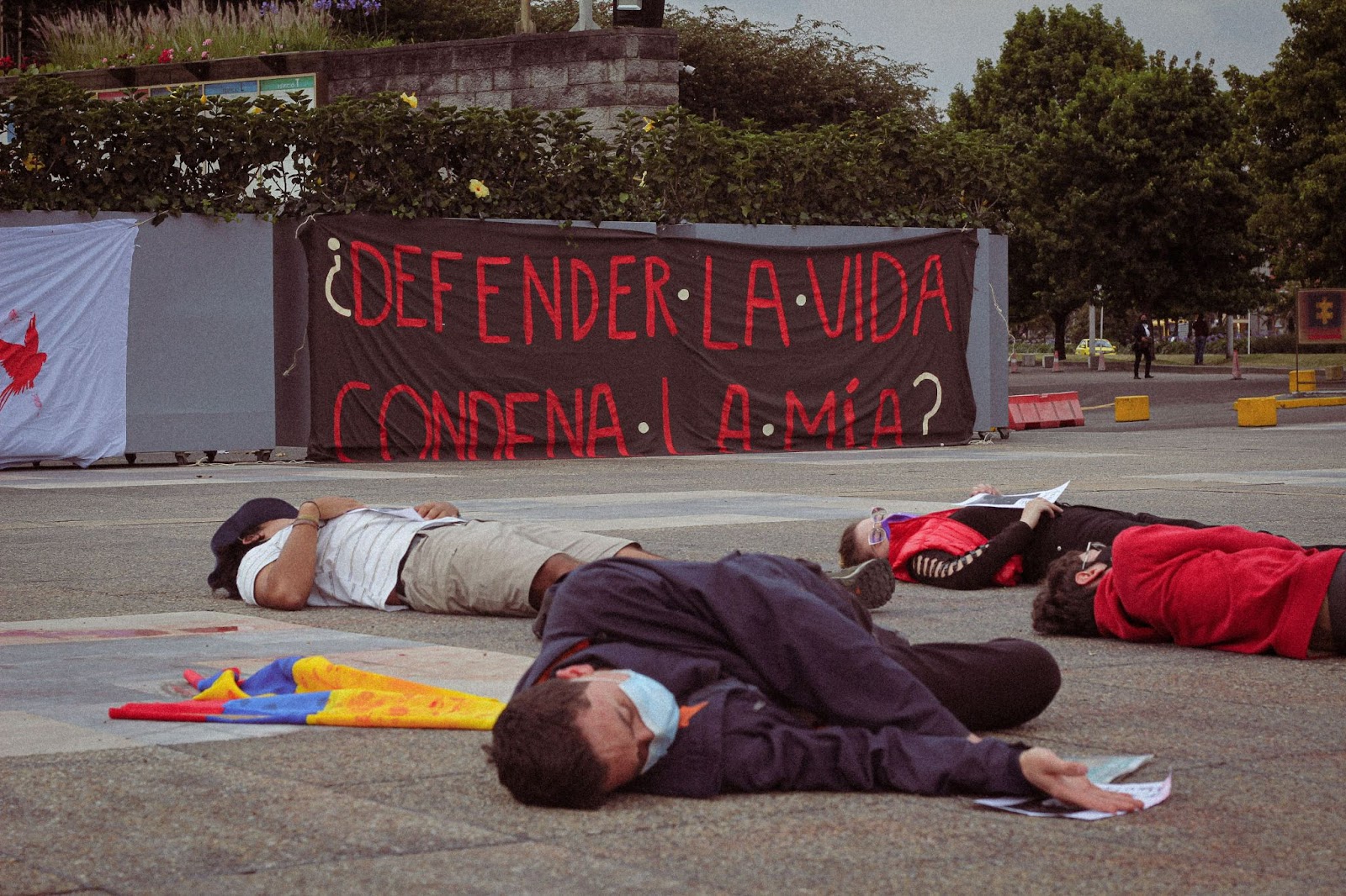 Rebels lie on the forecourt pretending to be dead beside a bloody Colombian flag.