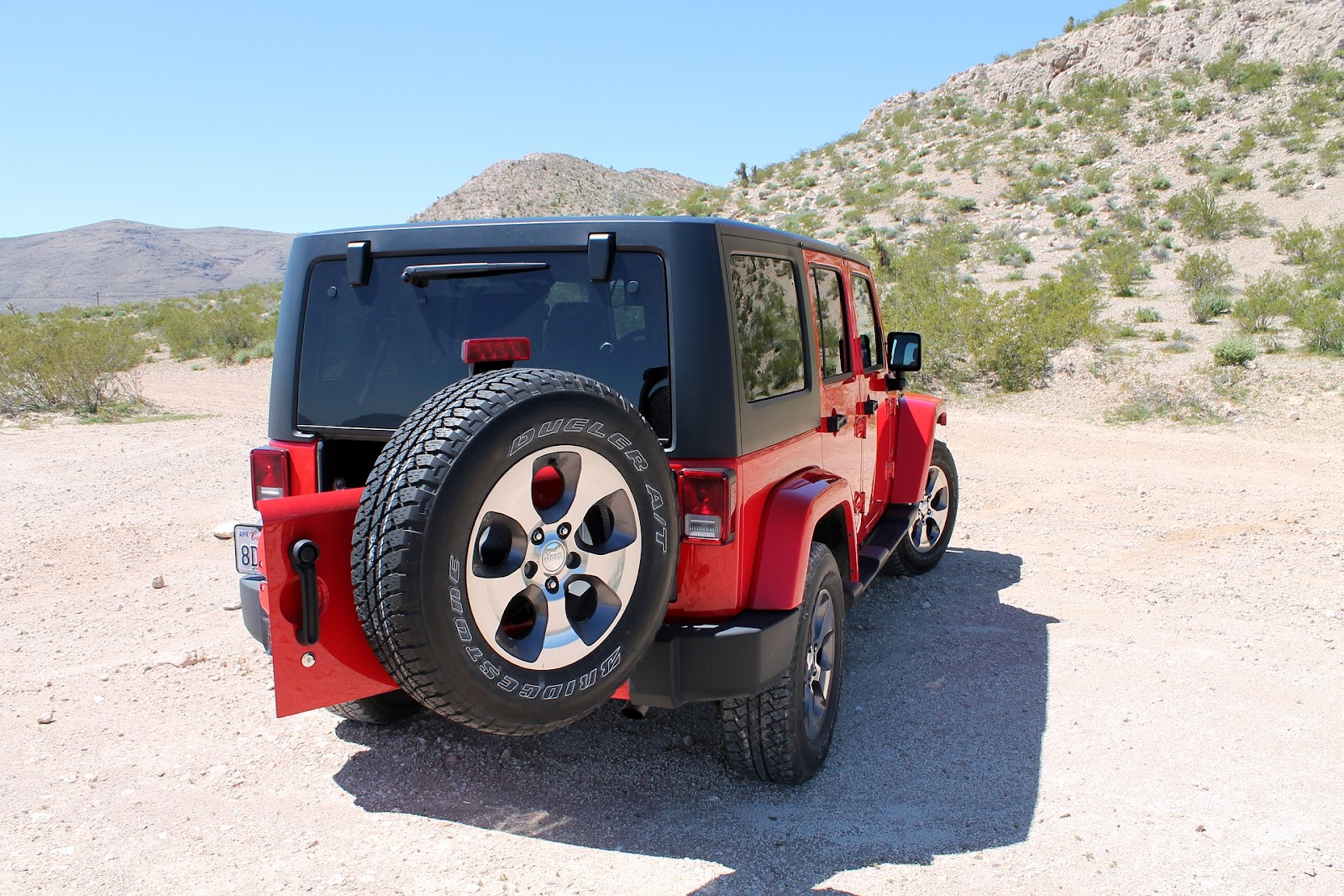 red jeep wrangler parked by hillside with back door open