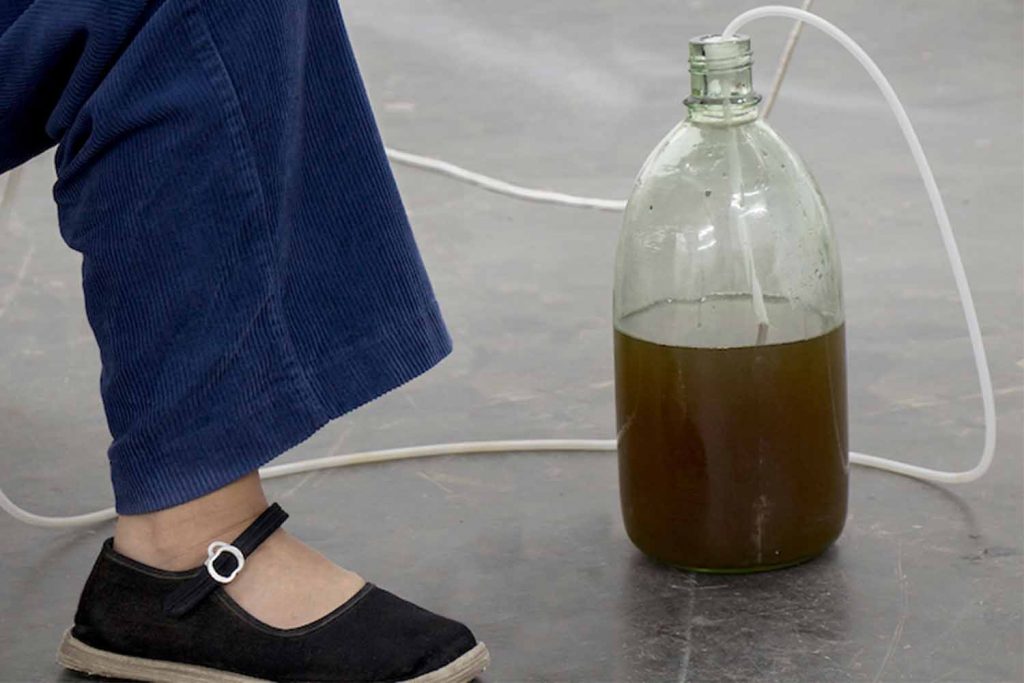 An image of artists Yu Ji's foot, a bottle, and a water pipe.