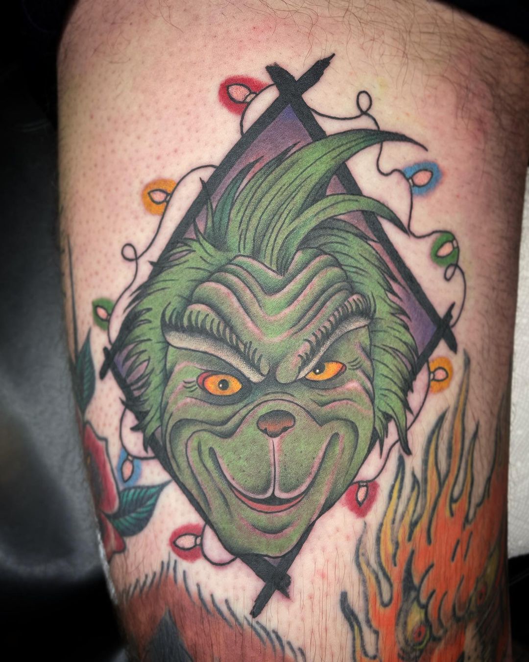 Smiling Grinch Face With Christmas Lights Tattoo