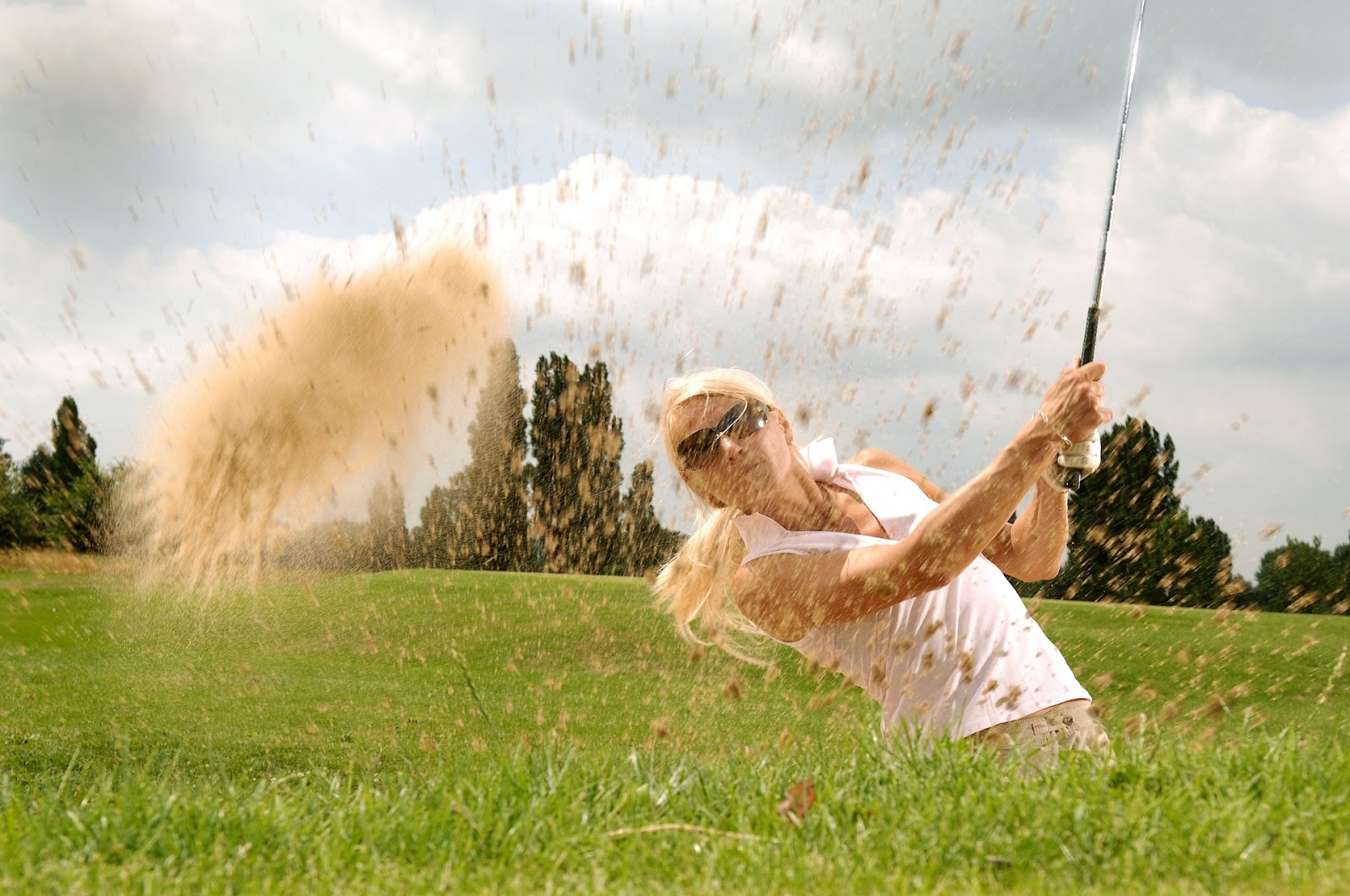 Woman hitting a golf ball on her golfing holidays 