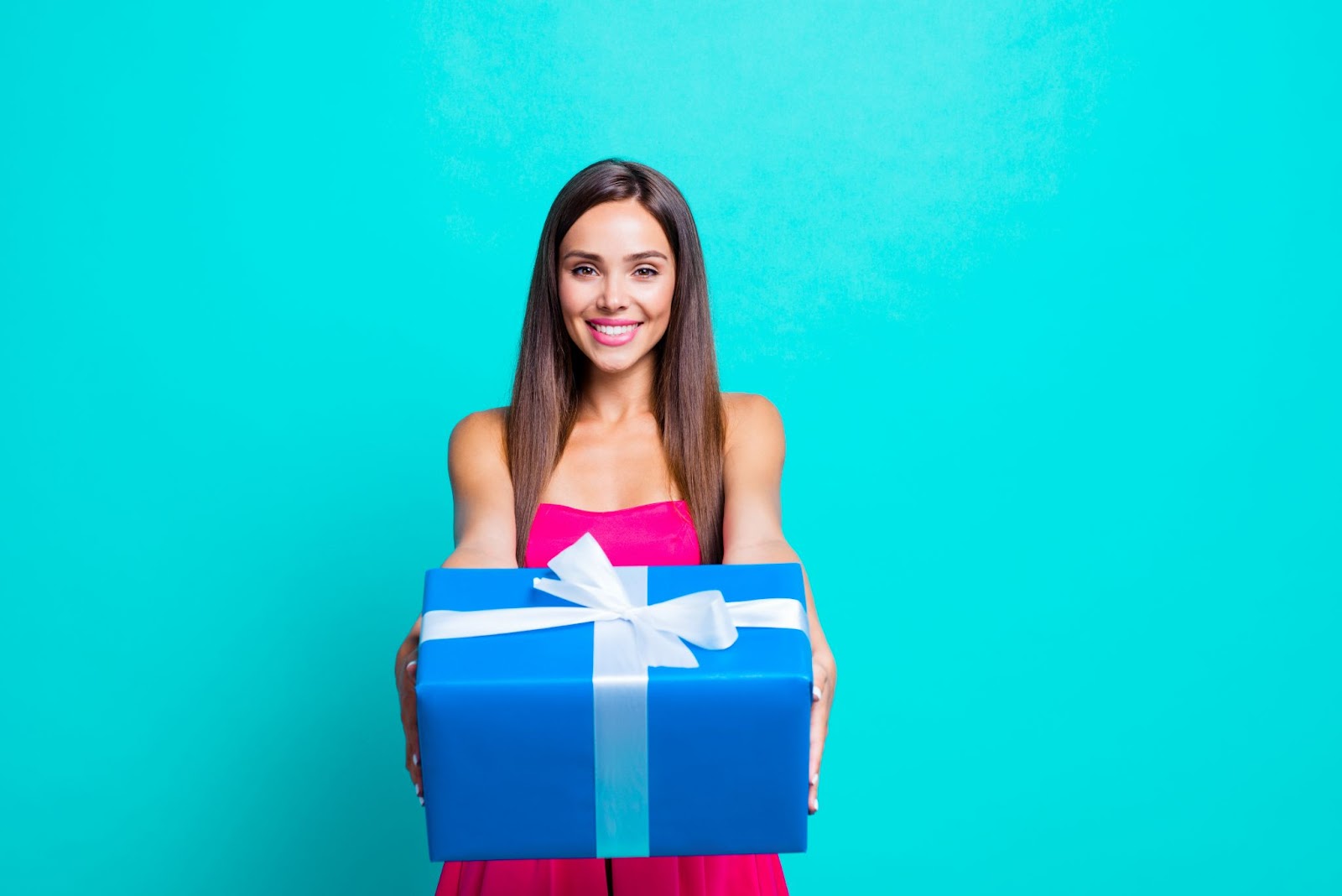 A woman holding out a gift-wrapped box.