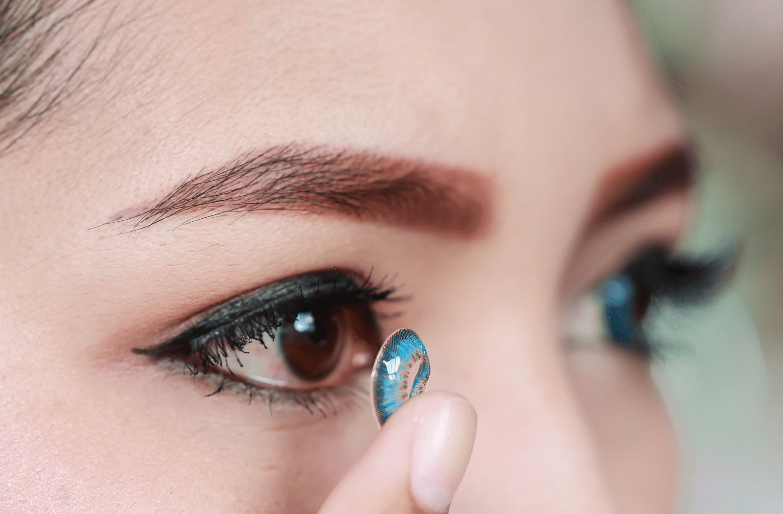 A woman putting in blue colored contact lenses