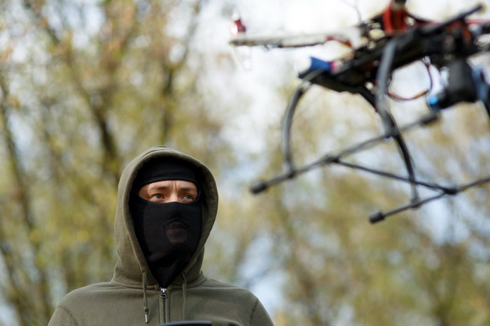 Man in mask operating a drone with remote control. Crime concept