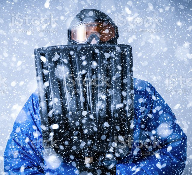 A person in a blue suit and goggles holding a black object in front of him

Description automatically generated