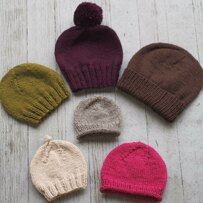 six knitted hats lying flat on wooden background