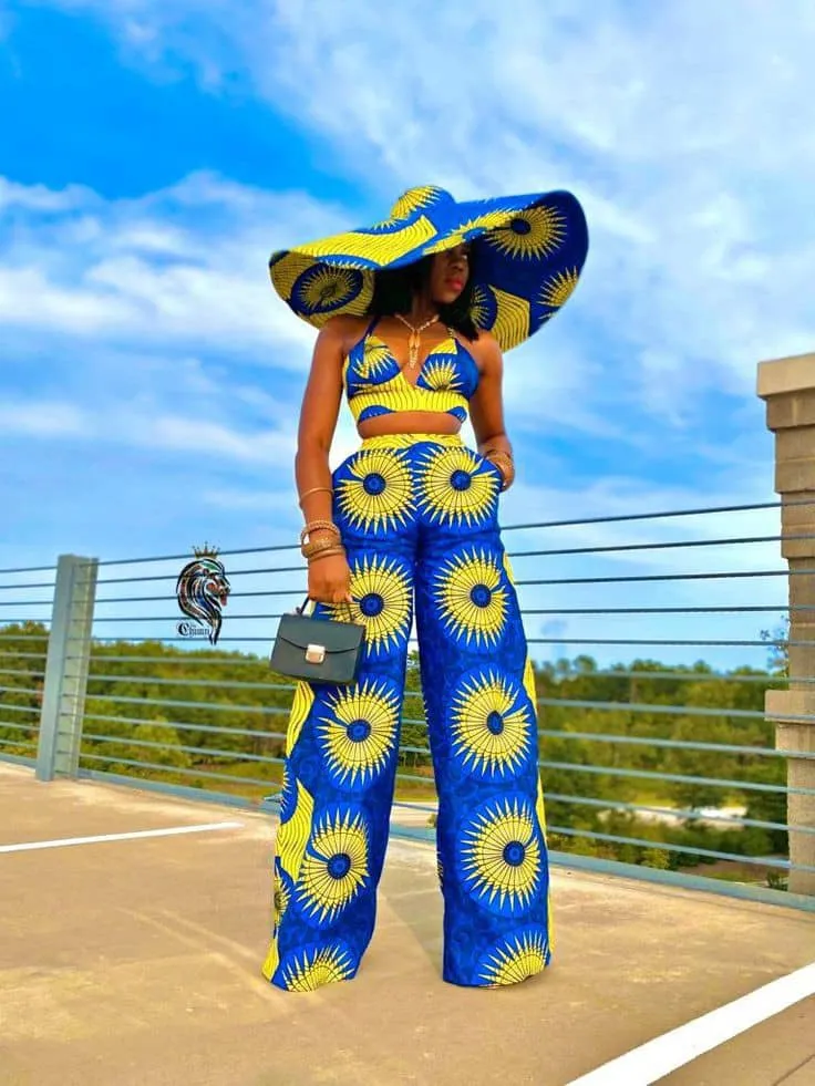 Woman wearing crop top and pants with wide-brimmed Ankara hat