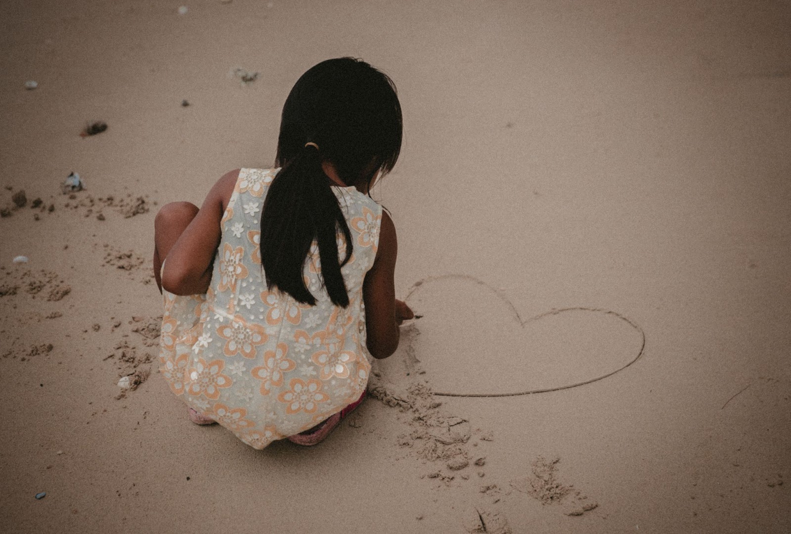 girl drawing heart at the beach